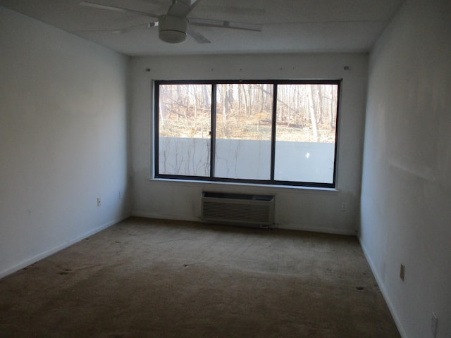 carpeted spare room with a ceiling fan, a wall mounted air conditioner, a healthy amount of sunlight, and baseboards