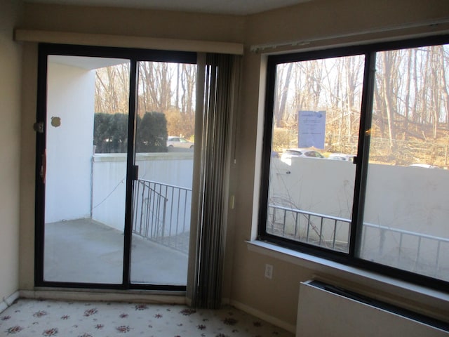 doorway to outside with radiator heating unit and baseboards