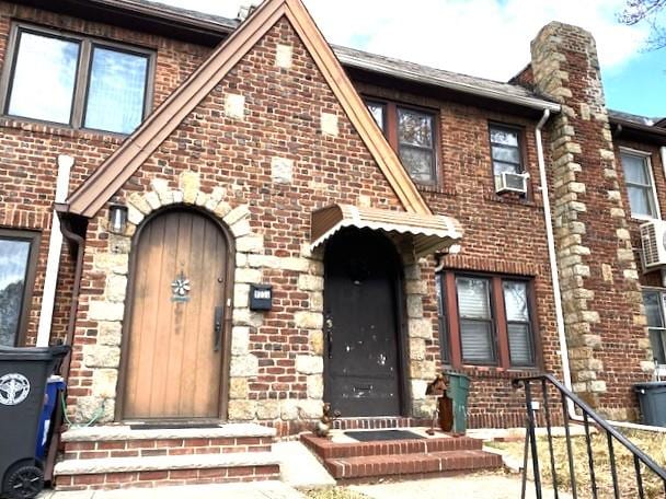 view of front of property featuring brick siding, a chimney, and cooling unit