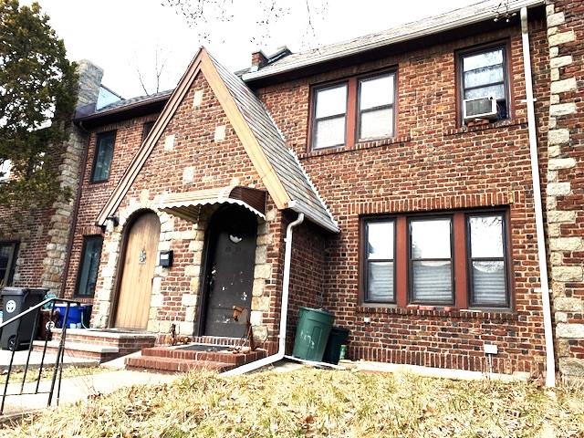 tudor house featuring cooling unit and brick siding