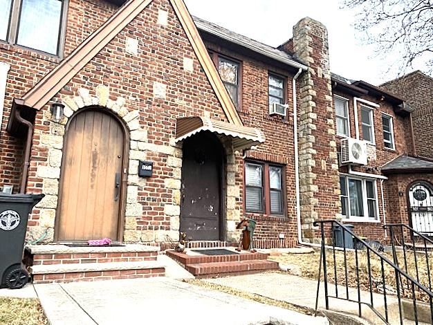 view of front of home featuring ac unit, a chimney, and brick siding