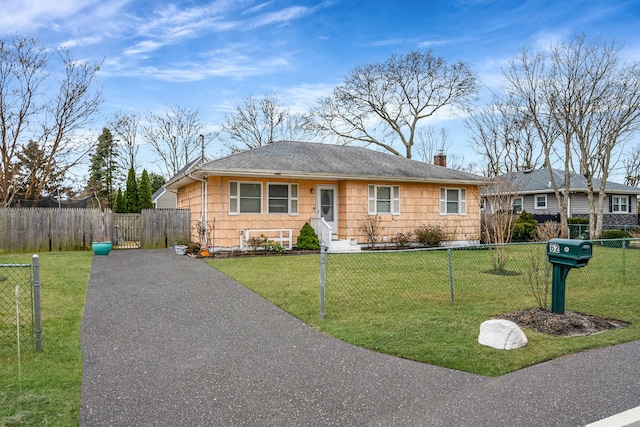 ranch-style home with a fenced front yard, a chimney, aphalt driveway, roof with shingles, and a front yard