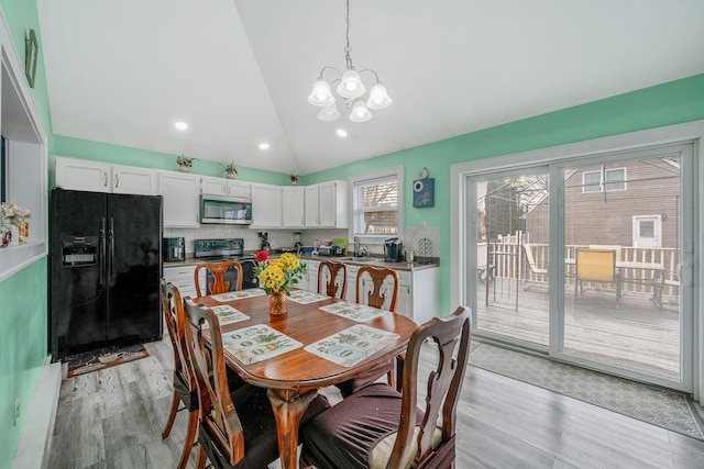 dining space with lofted ceiling, recessed lighting, light wood-style flooring, and an inviting chandelier