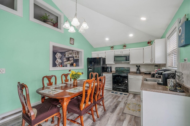 dining space featuring lofted ceiling, a notable chandelier, light wood finished floors, and recessed lighting