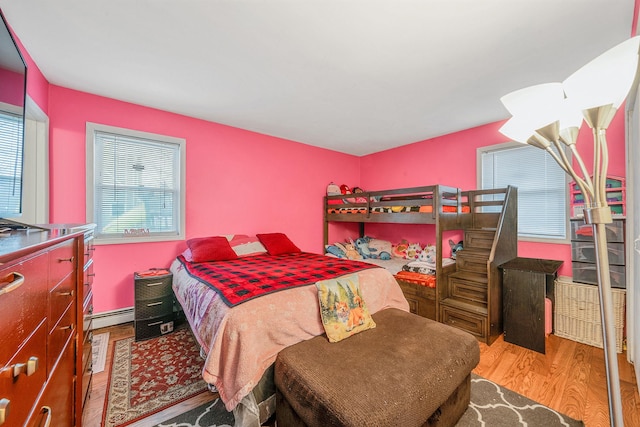 bedroom with baseboard heating and wood finished floors