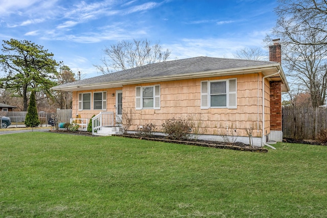 ranch-style home featuring roof with shingles, a chimney, fence, and a front yard