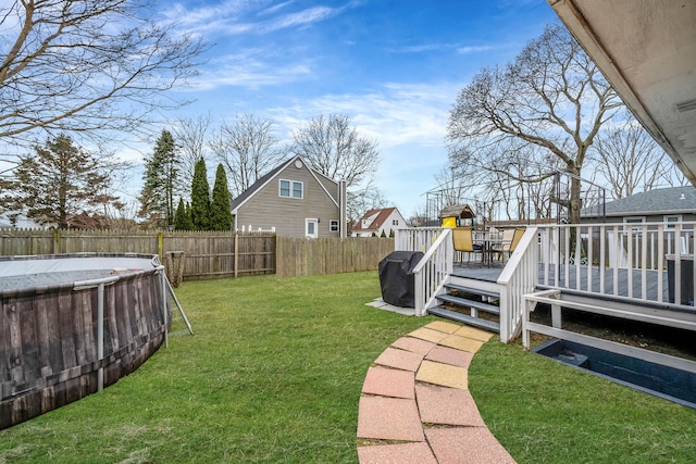 view of yard with a fenced backyard, a deck, and a fenced in pool