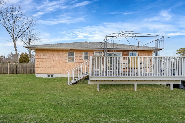 rear view of property with fence, a deck, and a lawn