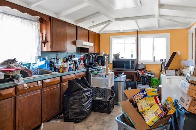 kitchen featuring under cabinet range hood, stainless steel microwave, coffered ceiling, backsplash, and beamed ceiling