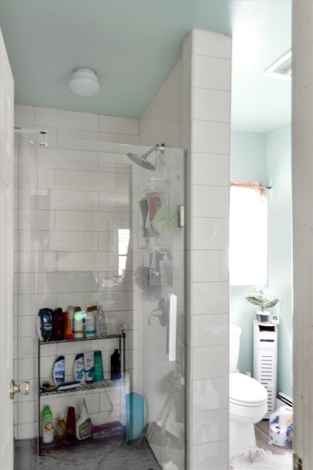 bathroom with toilet, a stall shower, visible vents, and baseboard heating