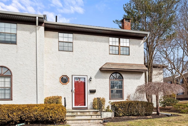 view of front of house with a chimney and stucco siding