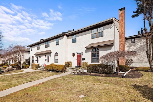 multi unit property with a chimney, a front yard, and stucco siding