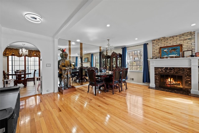 dining space featuring a chandelier, arched walkways, a fireplace, and hardwood / wood-style flooring