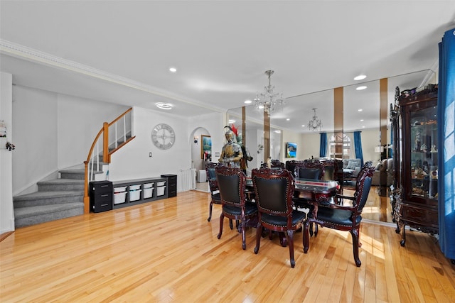 dining space featuring arched walkways, recessed lighting, a notable chandelier, wood finished floors, and stairway