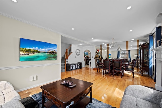 living area featuring arched walkways, light wood finished floors, stairs, and ornamental molding