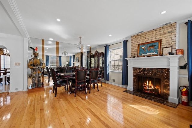 dining room with wood-type flooring, a premium fireplace, visible vents, and a chandelier