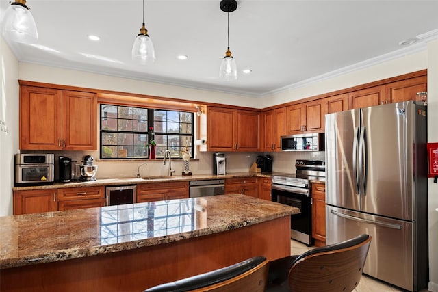 kitchen featuring brown cabinets, crown molding, appliances with stainless steel finishes, stone countertops, and a sink