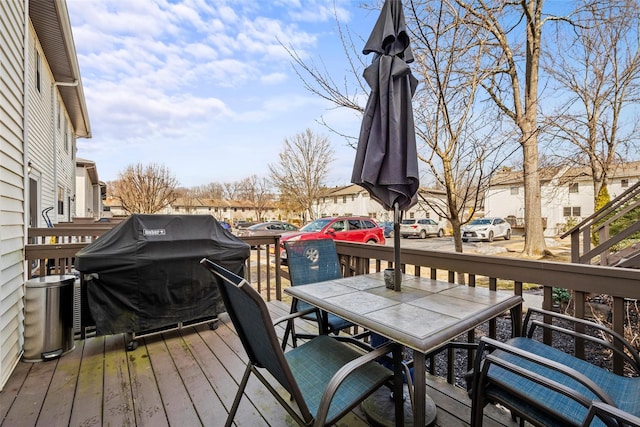 wooden terrace with outdoor dining area, grilling area, and a residential view