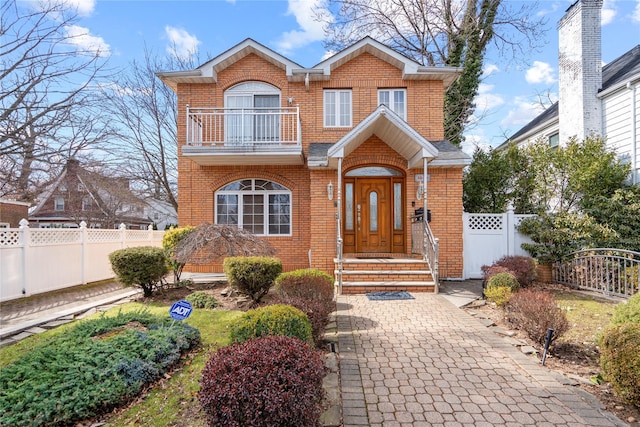 view of front of home with a balcony, fence private yard, and brick siding