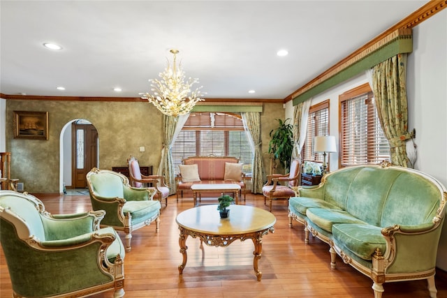 sitting room with ornamental molding, arched walkways, an inviting chandelier, and wood finished floors