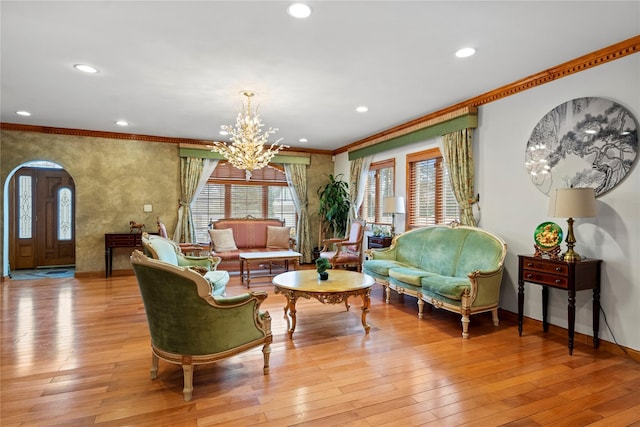 sitting room featuring arched walkways, crown molding, recessed lighting, light wood-style flooring, and an inviting chandelier