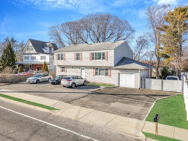 view of front of property with aphalt driveway, an attached garage, fence, and a shingled roof