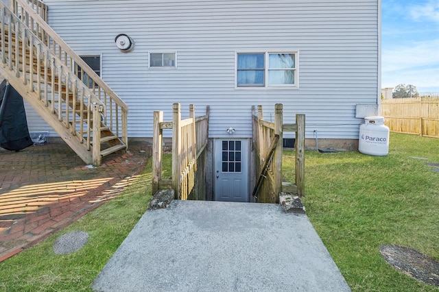 rear view of property with stairway, fence, and a lawn