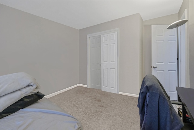 bedroom featuring lofted ceiling, carpet, baseboards, and a closet