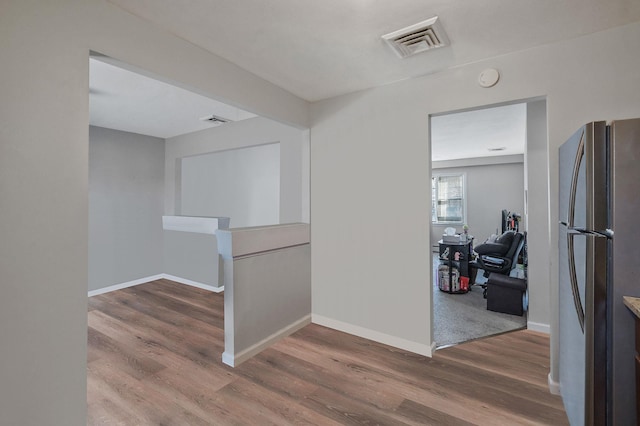 hallway featuring visible vents, baseboards, and wood finished floors