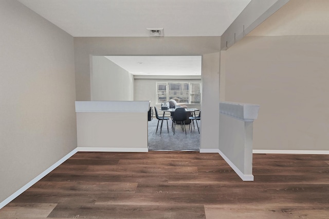 hallway featuring wood finished floors, visible vents, and baseboards