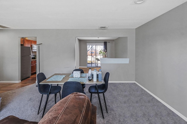 dining area featuring visible vents, dark carpet, and baseboards