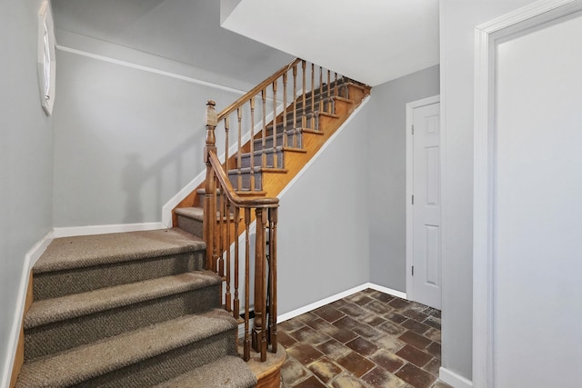 stairs featuring brick floor and baseboards