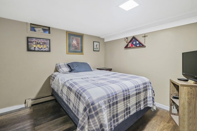 bedroom with baseboard heating, wood finished floors, and baseboards