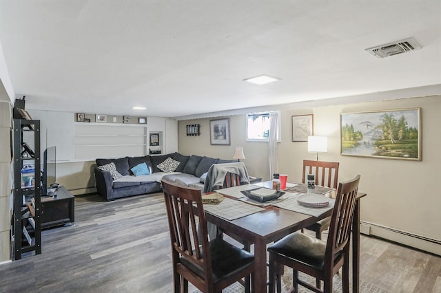 dining area with a baseboard radiator, visible vents, baseboard heating, and wood finished floors