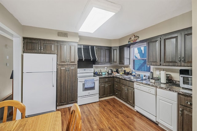 kitchen featuring white appliances, visible vents, wood finished floors, extractor fan, and dark brown cabinets