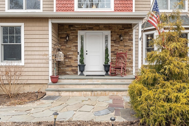 view of exterior entry featuring a tile roof, mansard roof, and a porch