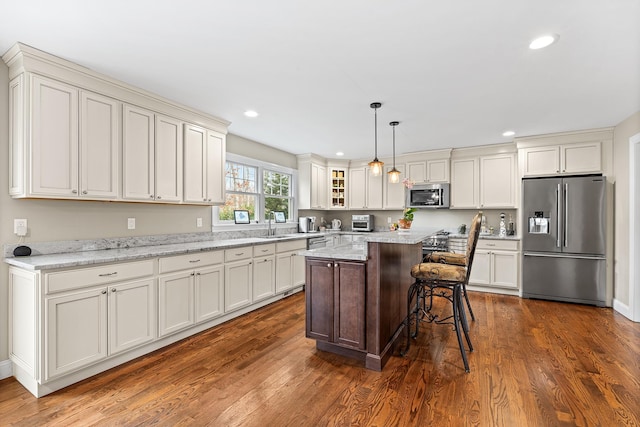 380 Hickory Rd, Southold, NY 11971 - kitchen featuring a kitchen island, glass insert cabinets, dark wood finished floors, a breakfast bar area, and appliances with stainless steel finishes