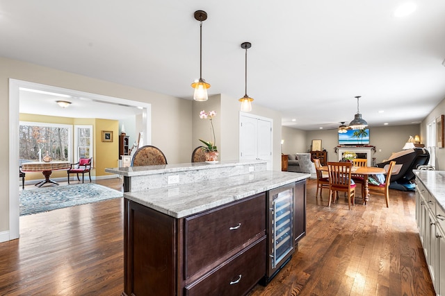 380 Hickory Rd, Southold, NY 11971 - kitchen featuring dark brown cabinetry, open floor plan, hanging light fixtures, a fireplace, and dark wood-style floors