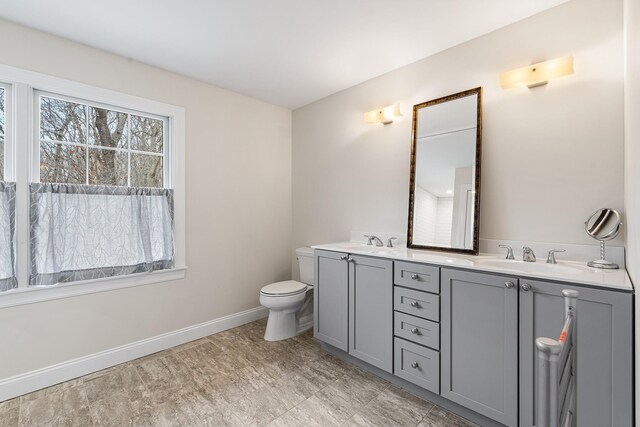 380 Hickory Rd, Southold, NY 11971 - bathroom featuring double vanity, toilet, baseboards, and a sink
