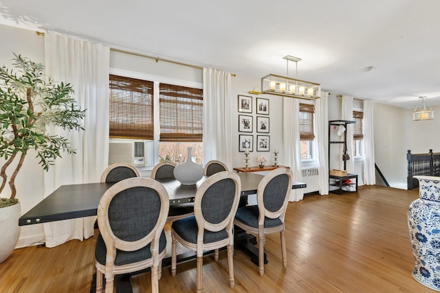 dining area with cooling unit, an inviting chandelier, wood finished floors, and radiator heating unit