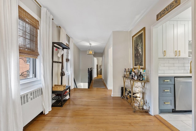 hallway with light wood-type flooring and radiator heating unit