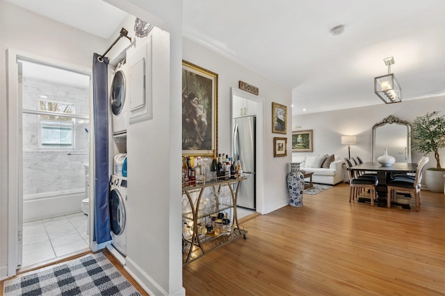 entryway with stacked washing maching and dryer, light wood-type flooring, and baseboards