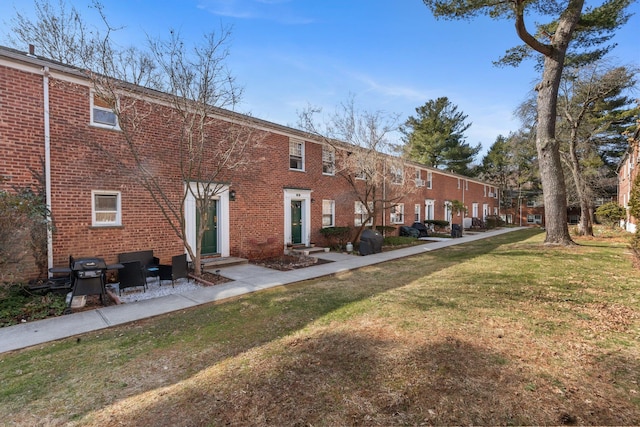 back of property featuring entry steps, a yard, and brick siding