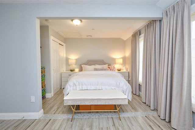 bedroom with light wood-style flooring, baseboards, and vaulted ceiling