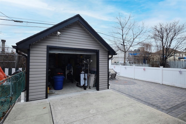 detached garage with fence and concrete driveway