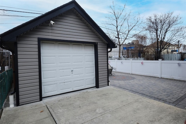 detached garage with concrete driveway and fence