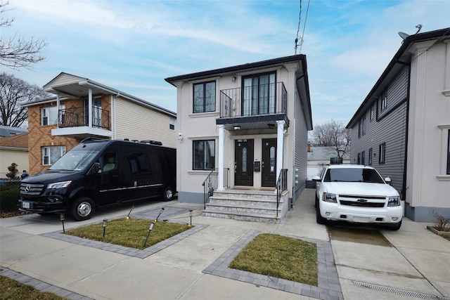 view of front of home with a balcony, concrete driveway, and stucco siding