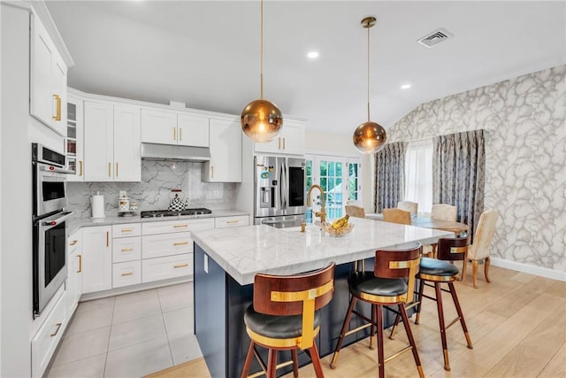 kitchen with under cabinet range hood, visible vents, appliances with stainless steel finishes, and white cabinets