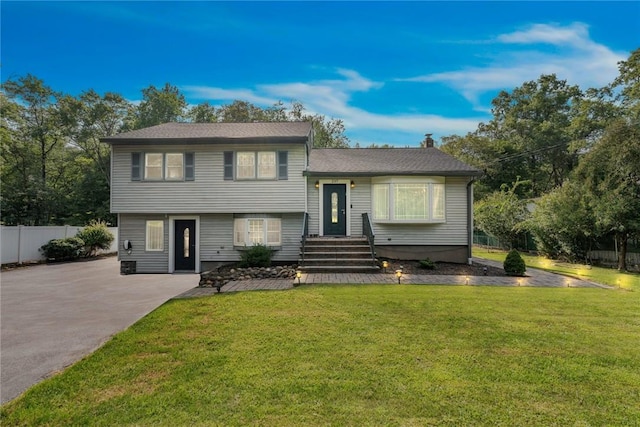 split level home with a front yard, fence, and a chimney