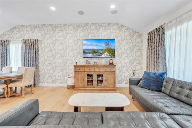 living area with lofted ceiling, light wood finished floors, a wealth of natural light, and baseboards